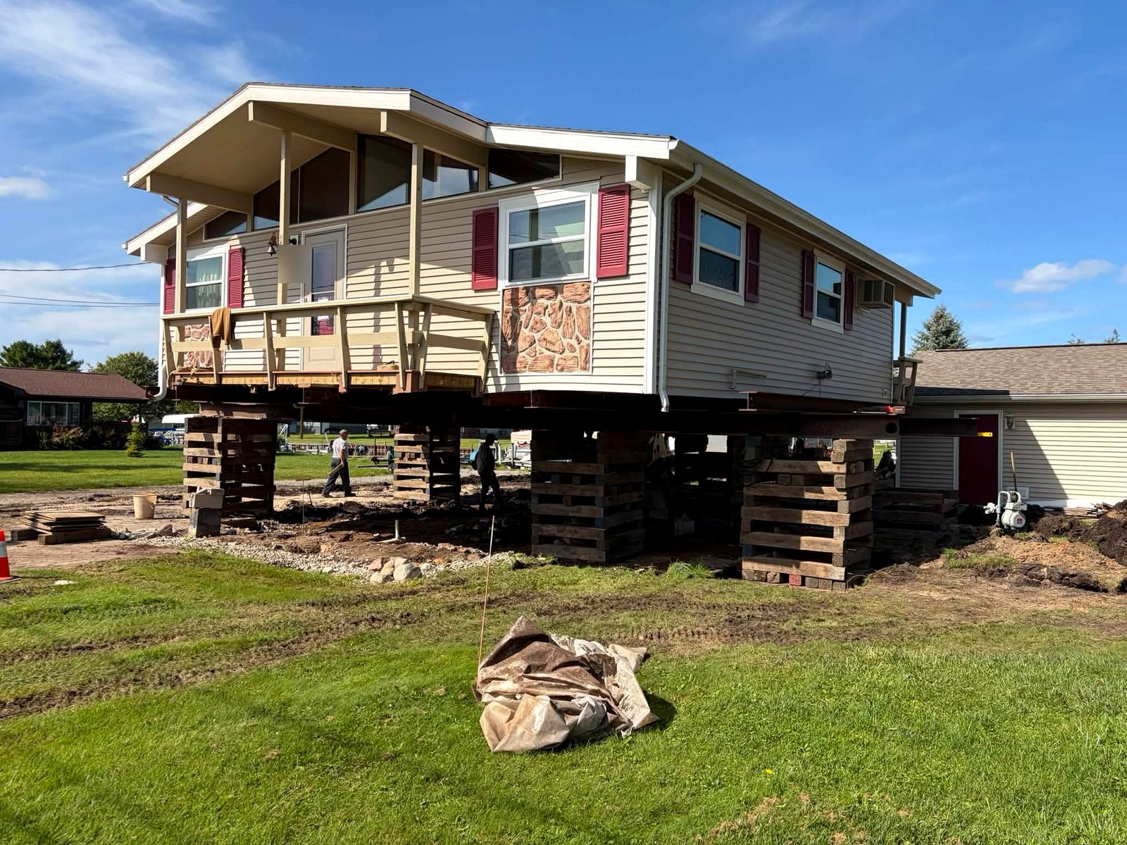 A house raised on timber cribbing and steel beams beside an open lawn